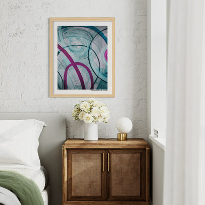Framed abstract art above a wooden cabinet with a vase of flowers in a bedroom setting.